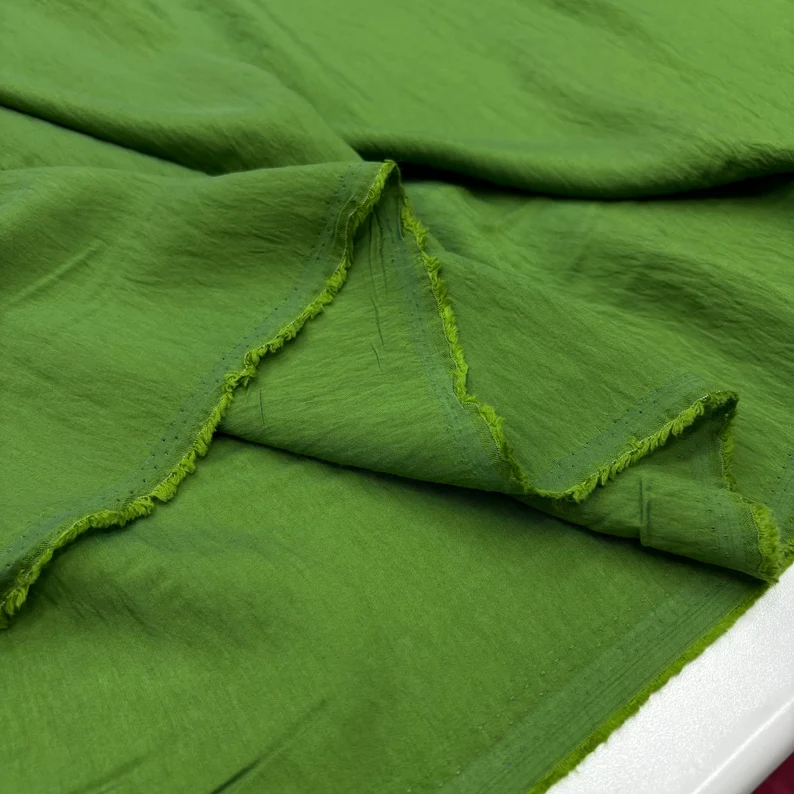 Close-up of green fabric showcasing its soft texture and lightweight weave.