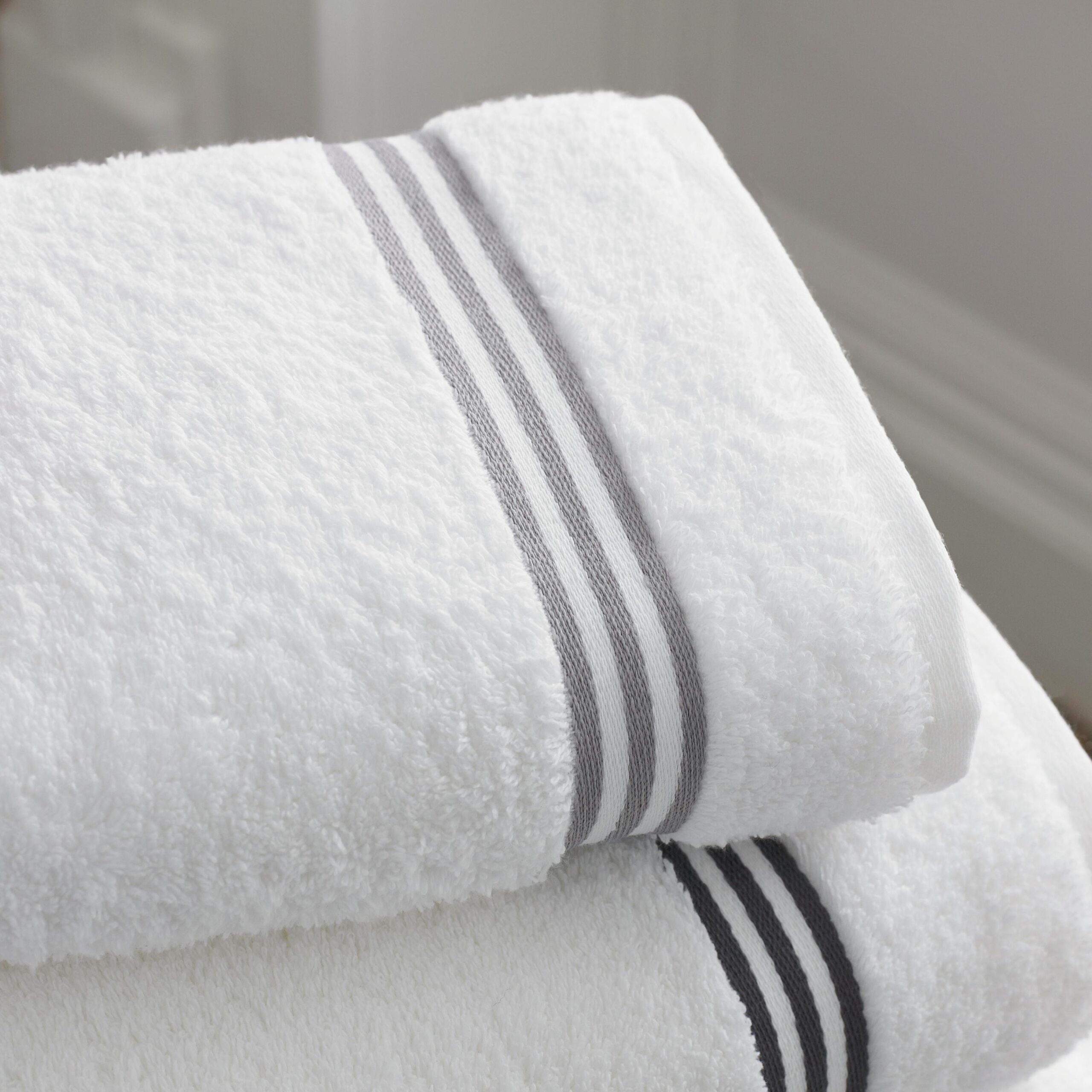 A stack of soft, white towels neatly folded on a wooden countertop.